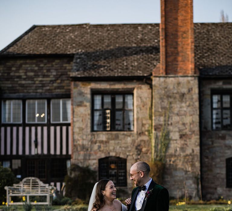 The bride and groom smile laughing at each other for their spring wedding at Brinsop Court Manor House and Barn