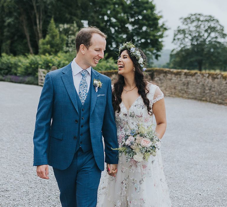 Indian British bride in a floral wedding dress and groom in a blue suit with floral tie at pastel wedding 