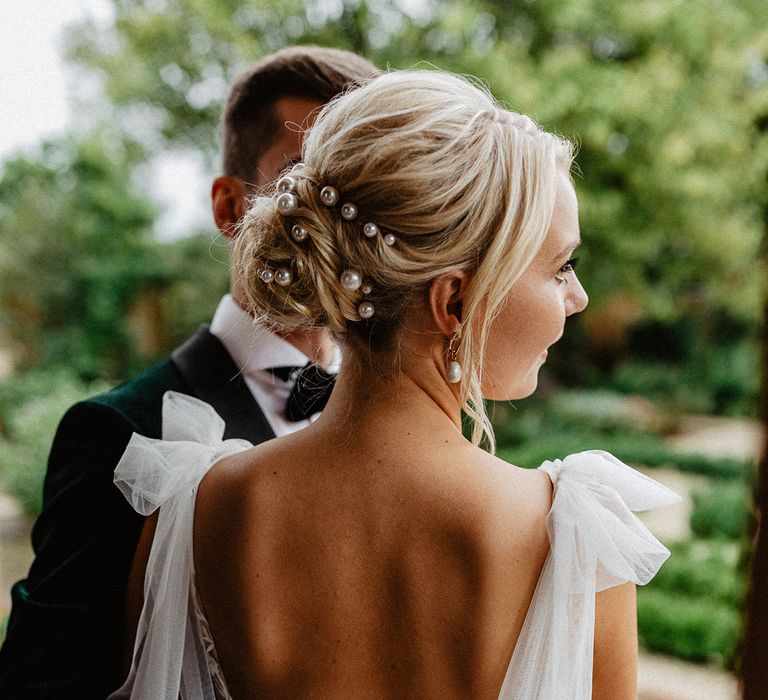 The bride in a low back wedding dress with pearl hair pins worn in her blonde hair in an updo for the rustic luxe Silchester Farm wedding 