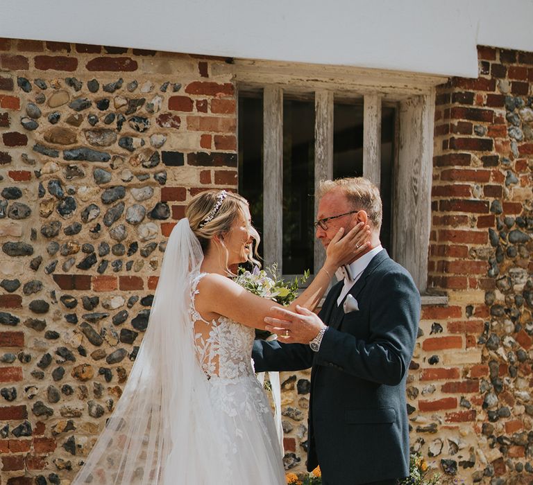 Father of the bride in navy suit and light grey bow tie sees the bride in her Dando London wedding dress for the first time 