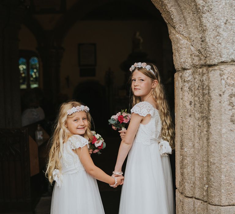 Flower girls in lace sleeve tulle dresses with pink sparkly shoes and flower crowns for the church wedding 