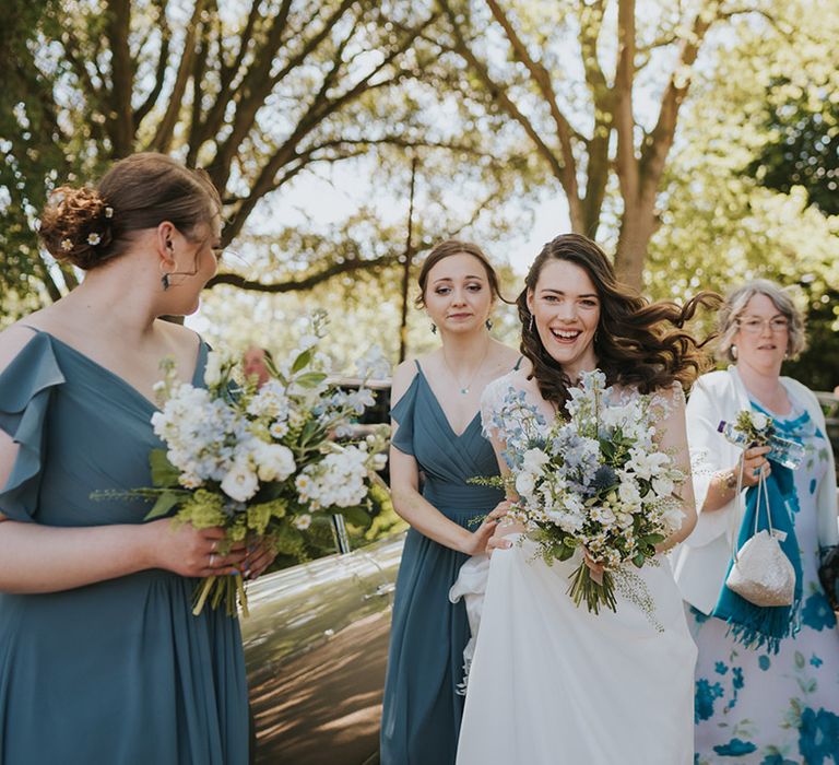 Blue bridesmaid dresses worn by the bridesmaids with a groomsman and wedding guest also wearing blue tones for the rustic wedding 