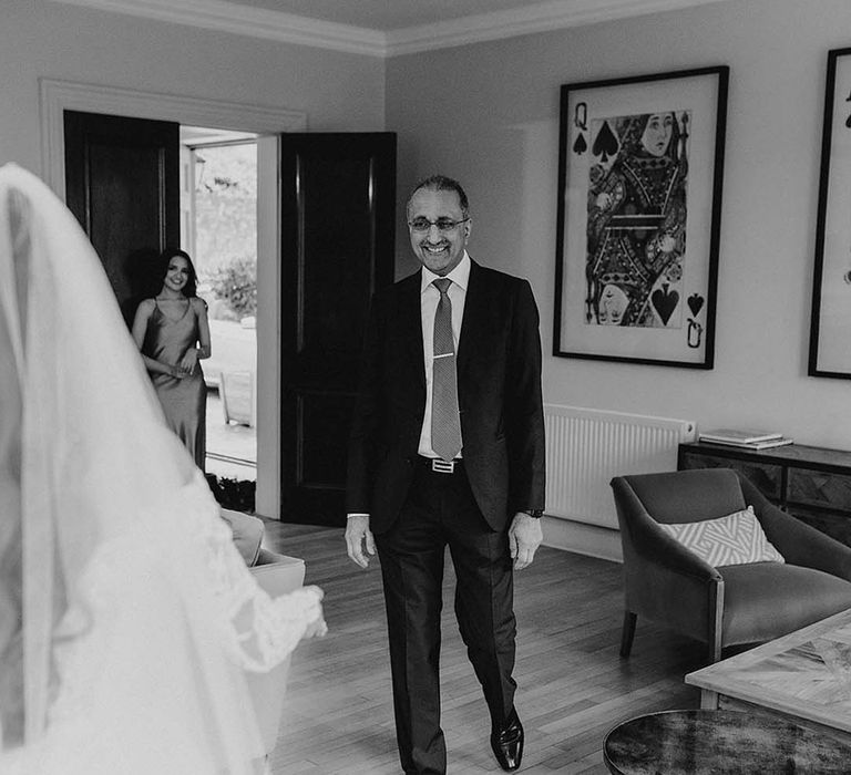 Father of the bride walks in beaming as he sees the bride in her wedding dress for the first time