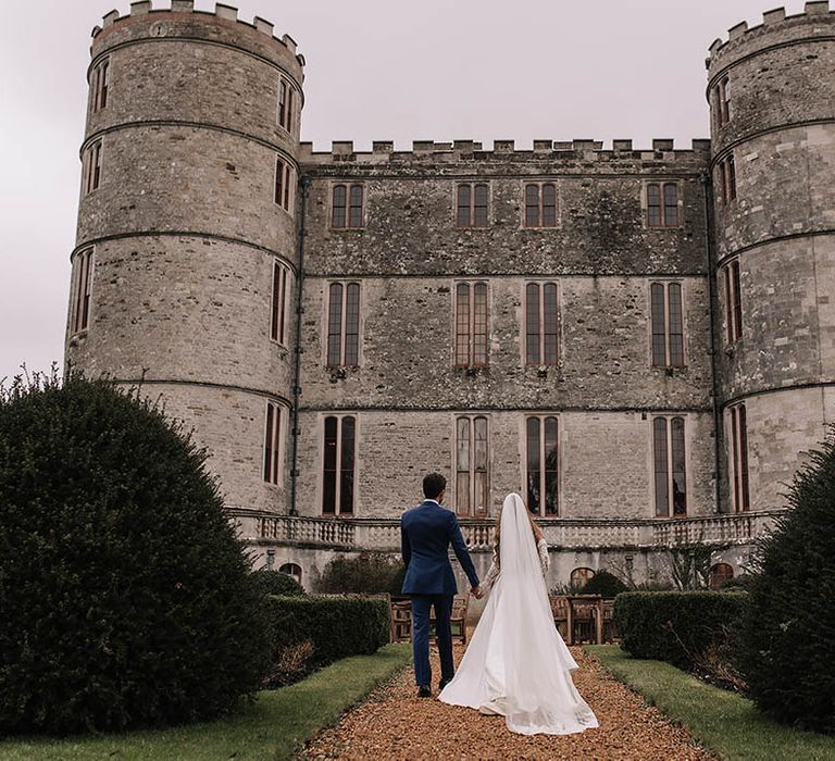 Lulworth Castle wedding venue in Dorset with the bride in an Eva Lendel wedding dress and groom in blue suit walking around