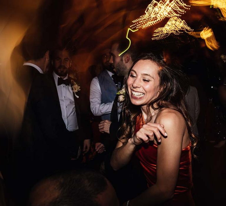 Wedding guest in one shoulder burnt orange bridesmaid dress dancing at wedding party at Brinsop Court wedding venue