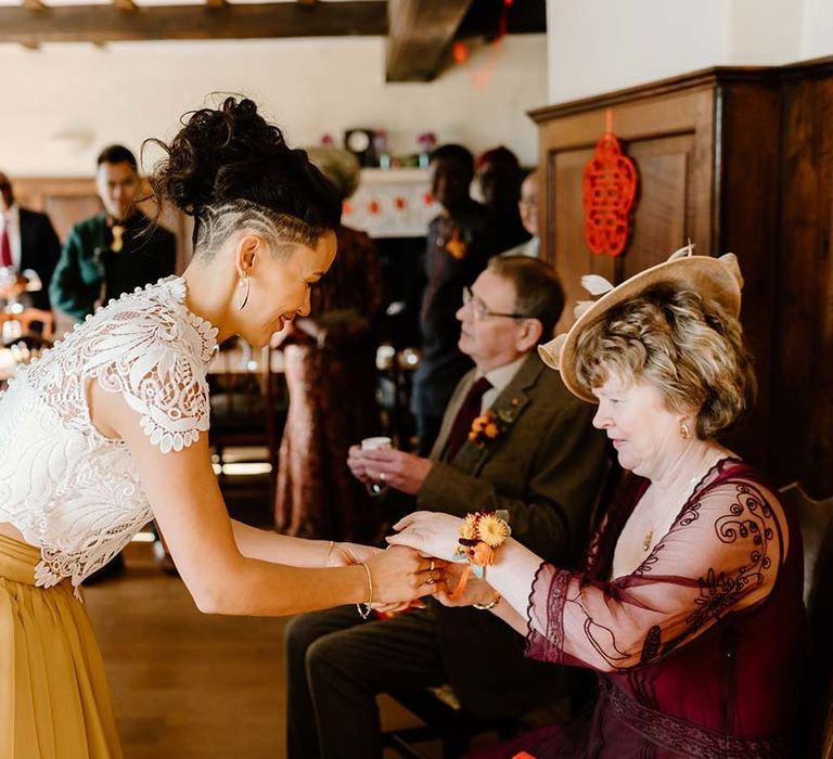 Bride at Broadfield Court in white mesh lace bridal crop top and yellow wedding skirt partaking in Chinese Tea Ceremony 