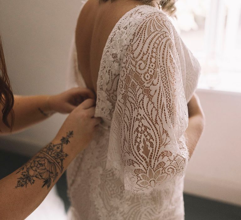 Bride in boho lace wedding dress with quarter length sleeves and pastel wildflower flower crown 