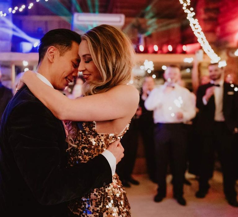 Bride in gold sequin sparkly reception dress dancing with groom in classic black tuxedo, black bowtie and white garden rose boutonniere at French destination wedding at La Cabane Des Praz 