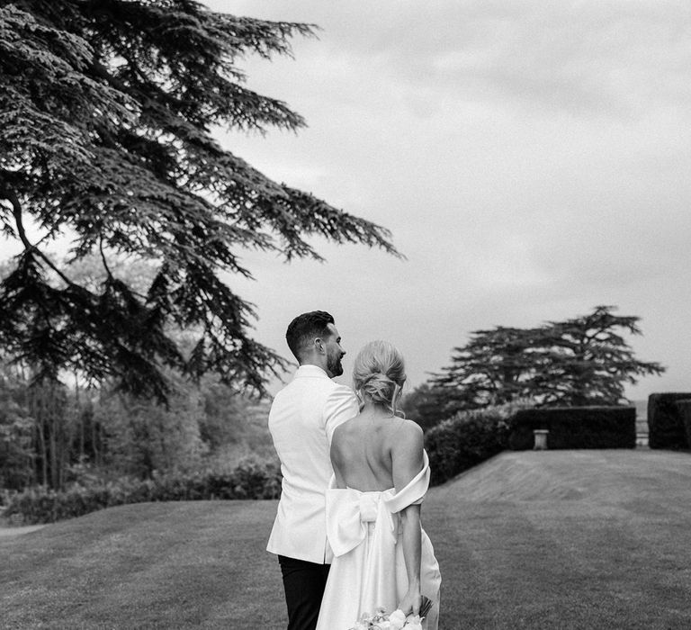 The bride and groom walk around their wedding venue to pose for their couple portrait 