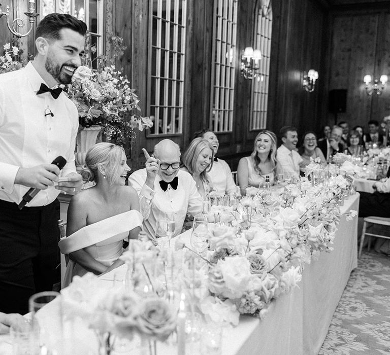 Classic wedding top table with the groom standing up reading out his wedding speech 