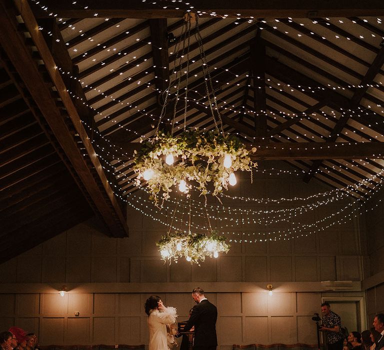 Fairy lights overhead and candle lanterns line the checkerboard aisle at Larkspur Lodge wedding 