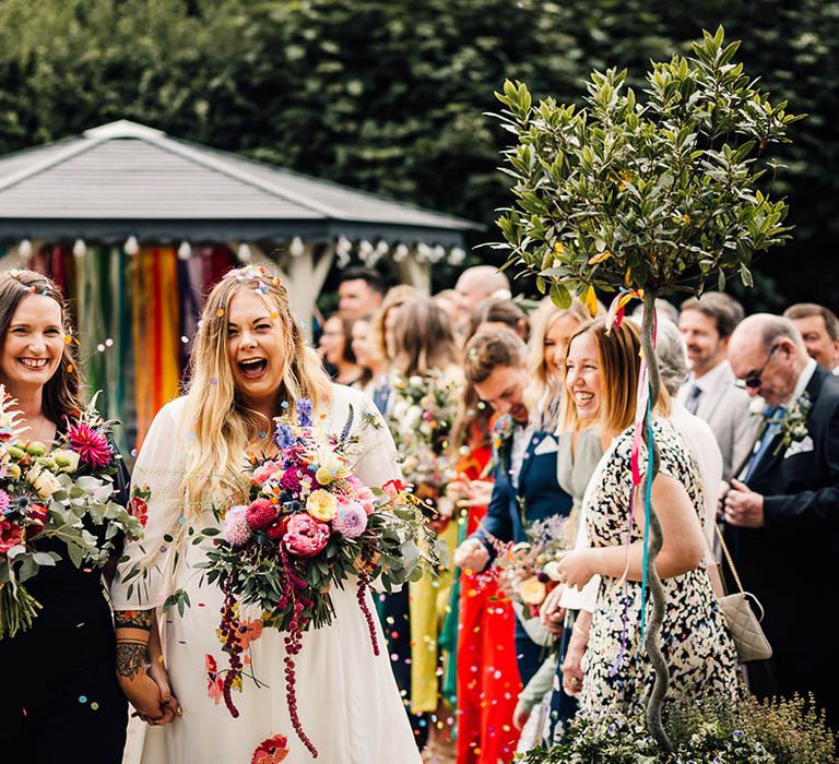 Lesbian wedding with two brides leaving the ceremony as a married couple as confetti is thrown 