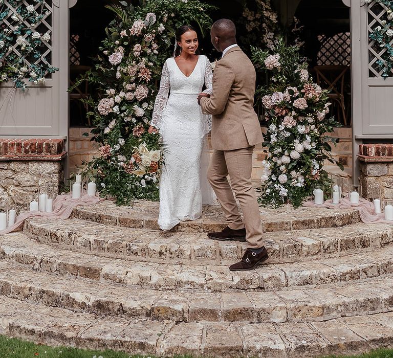 Outdoor wedding ceremony with the bride and groom at Port Lympne in Kent with pink flower decorations 