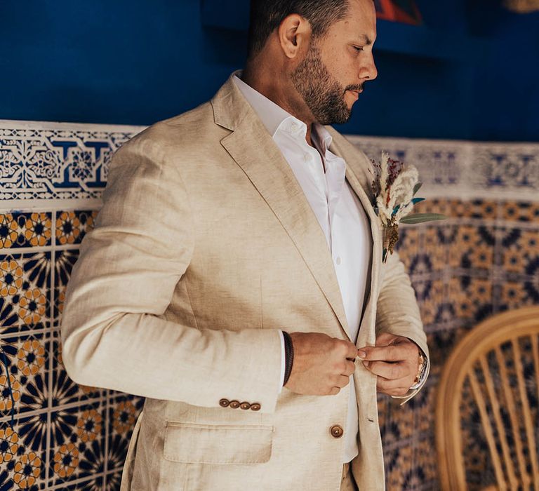 Groom in beige suit gets ready for the wedding 