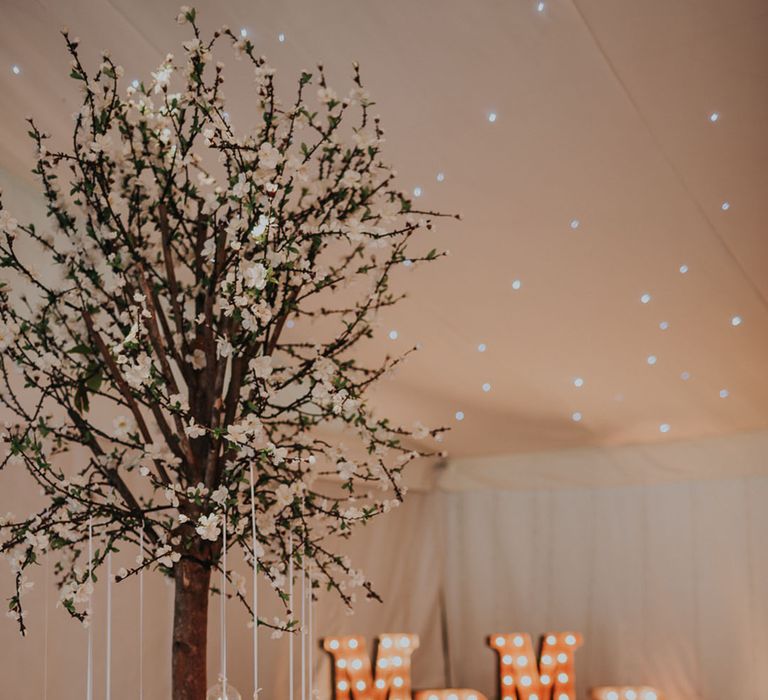 Mr & Mrs letter lights with tree centrepieces on tables with hanging tea lights 