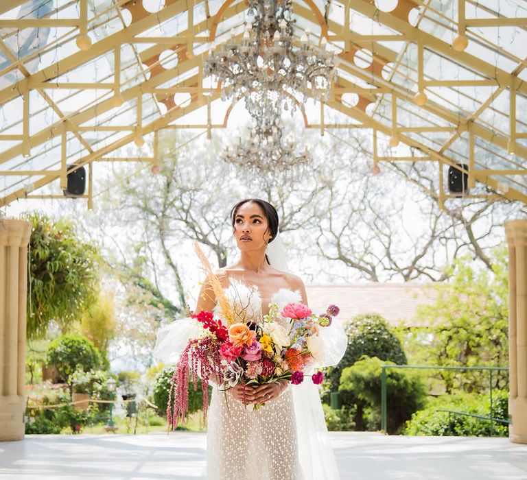 The bride in a strapless wedding dress holds a colourful bouquet at Shepstone Gardens venue 