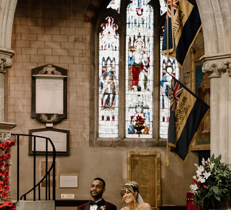 The bride and groom sit side by side at their church wedding ceremony 