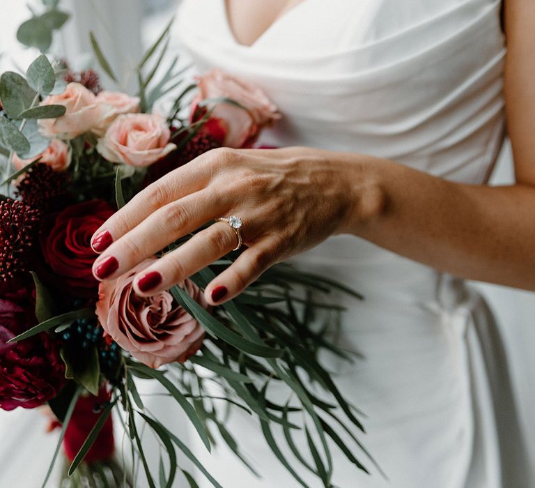 Bride with red wedding nails and diamond round brilliant engagement ring 