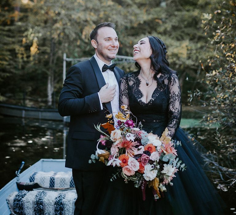 Groom in black tuxedo with the bride in a black wedding dress with autumnal bouquet 