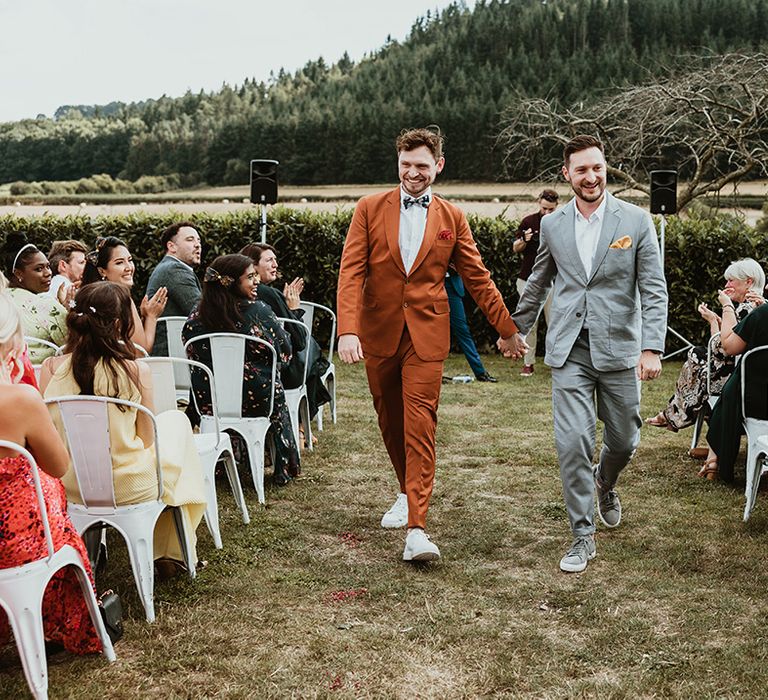 LGBTQI couple walk back down the aisle together at outdoor wedding at Wilde Lodge in Wales 