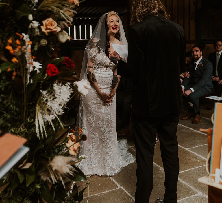 Bride laughs at the groom at their wedding ceremony with pampas grass and rose altar decorations 