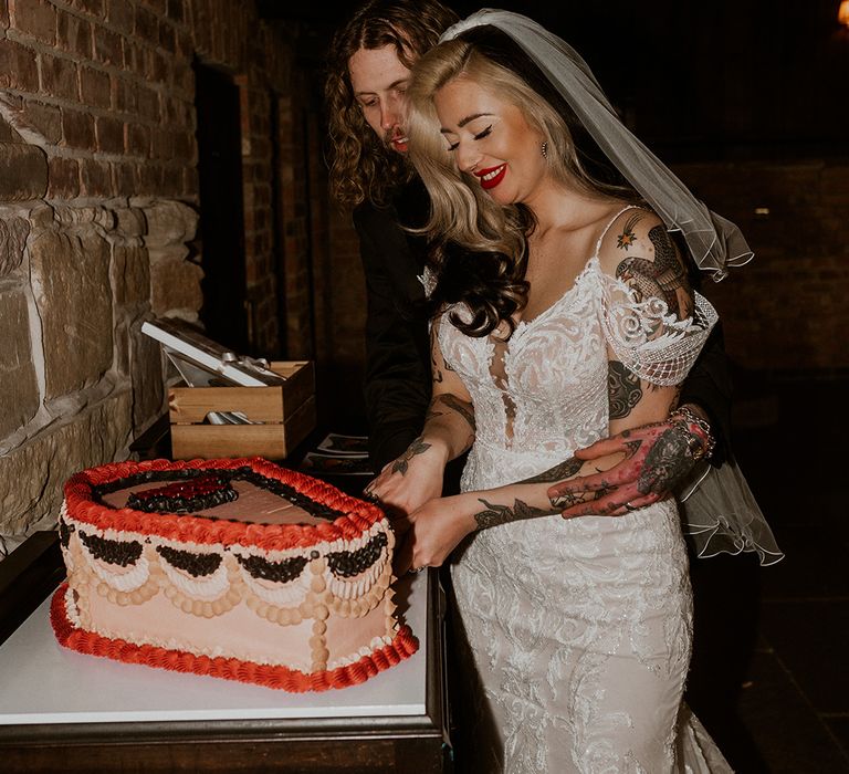 The newlyweds cut their coffin shaped wedding cake with 'til death do us part written in icing 