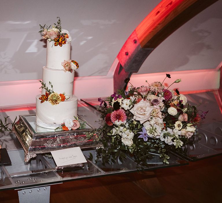 Three tier white iced wedding cake decorated with flowers made from Ghanian Kente cloth 