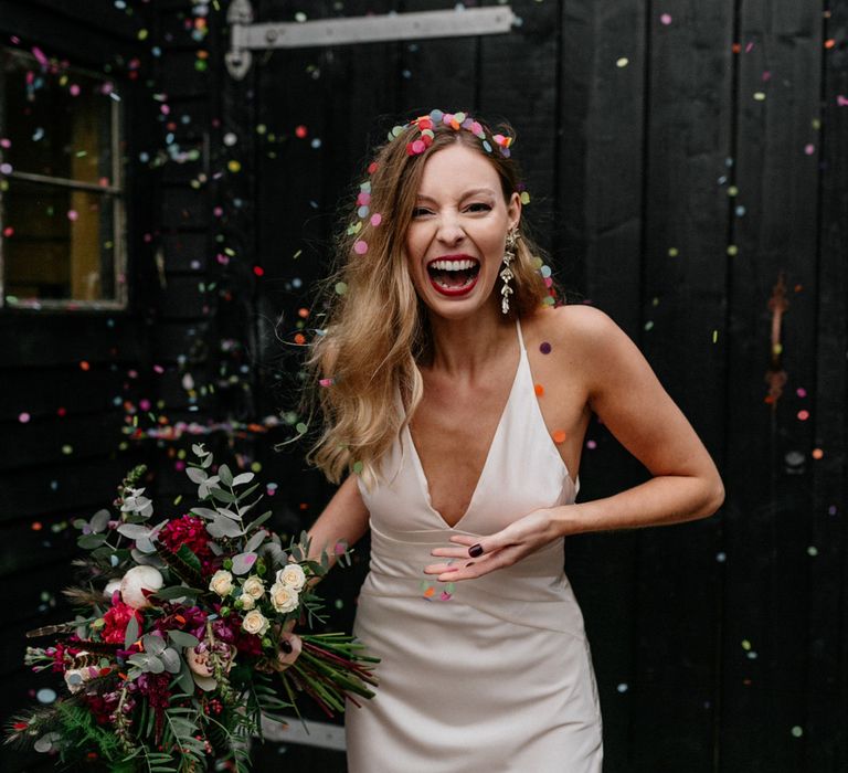 Bride in satin wedding dress covered in confetti at 2020 wedding