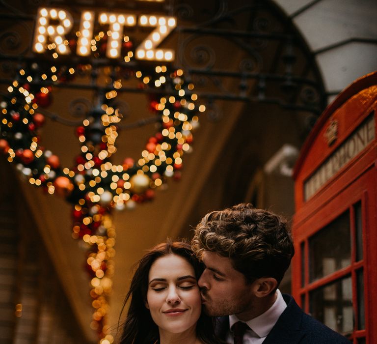 Groom kissing a bride in sheer sleeve wedding dress