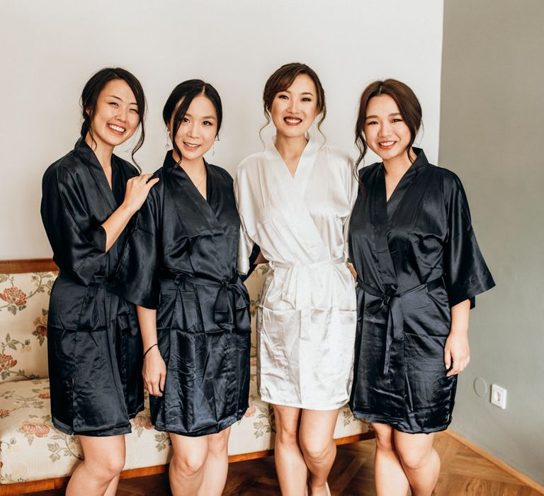 Bride and bridesmaids on the wedding morning in white and black getting ready robes 