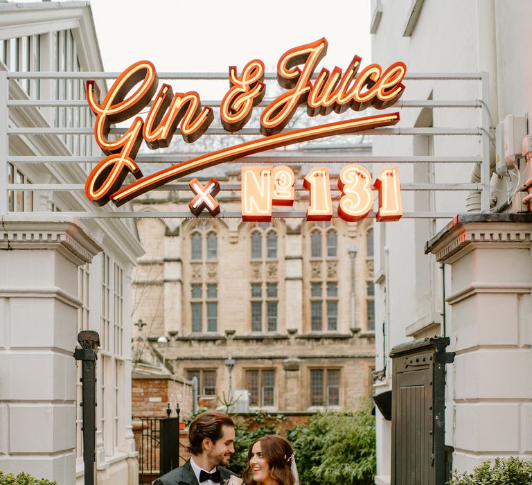 Newly-wed couple at No 131 Cheltemham wedding venue with gin and juice sign