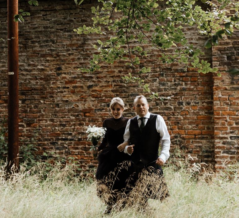 Bride walks with father in woodlands to ceremony