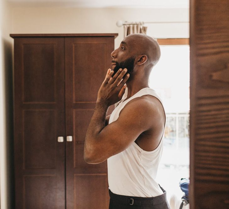 Black bearded groom in a white vest getting ready on the wedding morning 