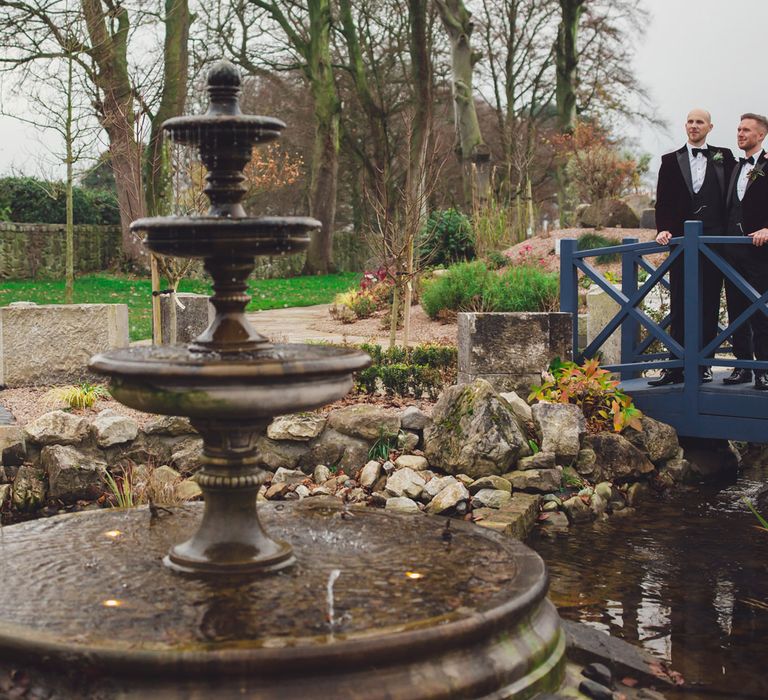 Portrait of two grooms in tuxedos on a bridge at Darver Castle Estate 