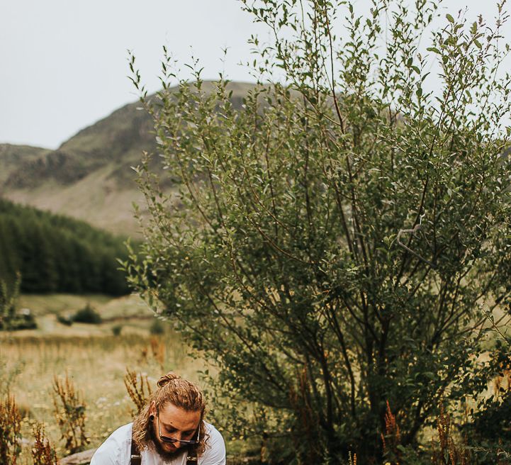 Groom puts on boots outdoors in the Lake District