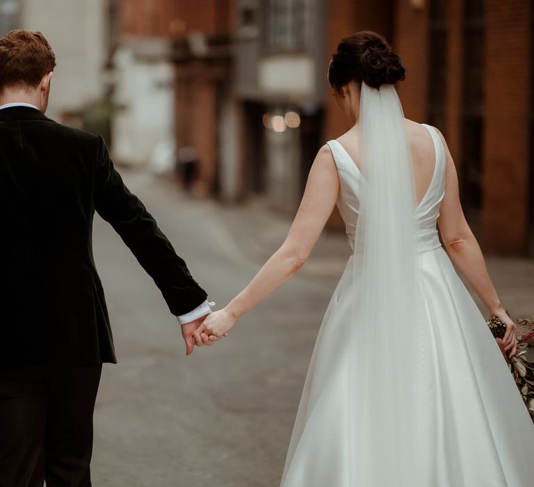 Bride and groom holding hands on Manchester street 