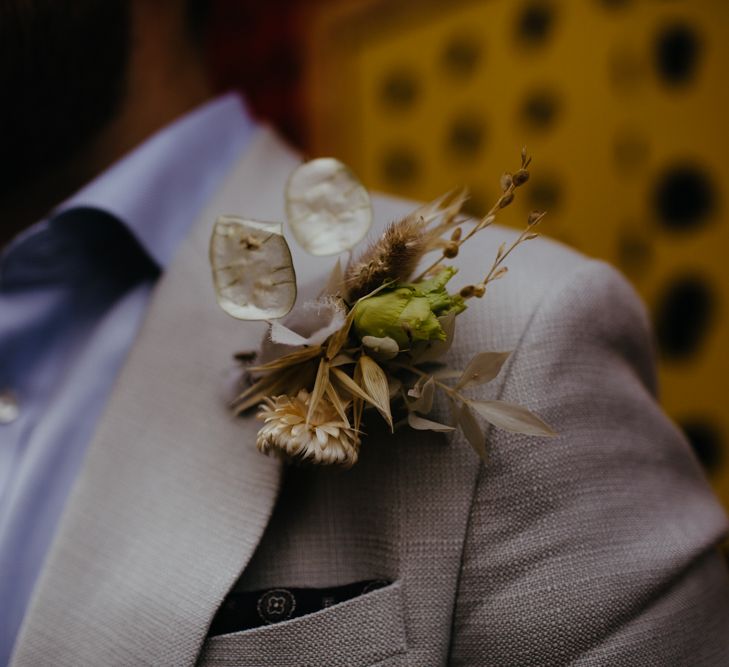 Close up of groom's grey jacket with peach buttonhole florals