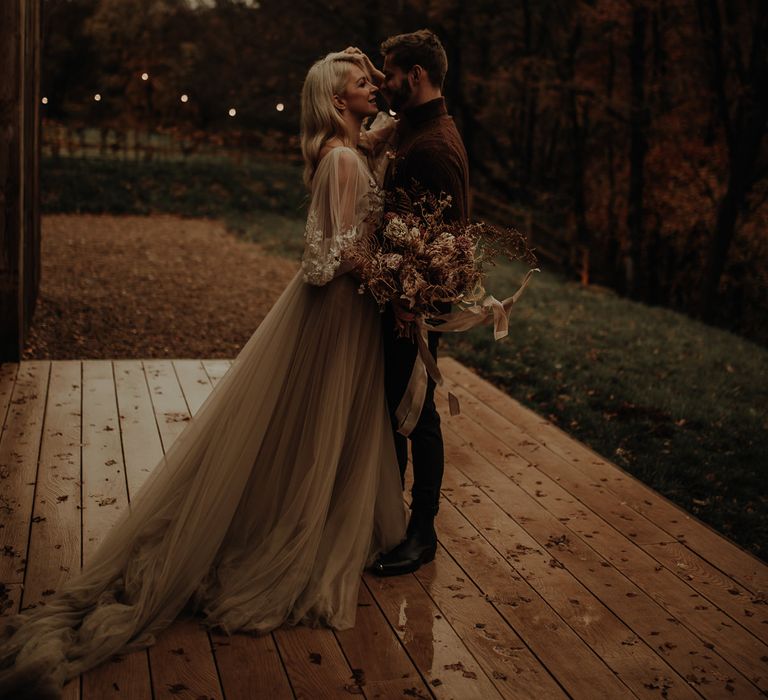 Bride and groom portrait outside Hidden River Cabins wedding venue with bride in a floaty chiffon wedding dress and groom in a jumper 