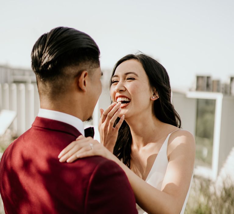 Beautiful bride laughing and smiling as she sees her groom for the first time at their first look 