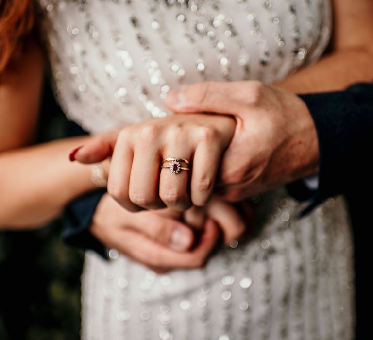 Bride & groom hold hands as they wear wedding rings