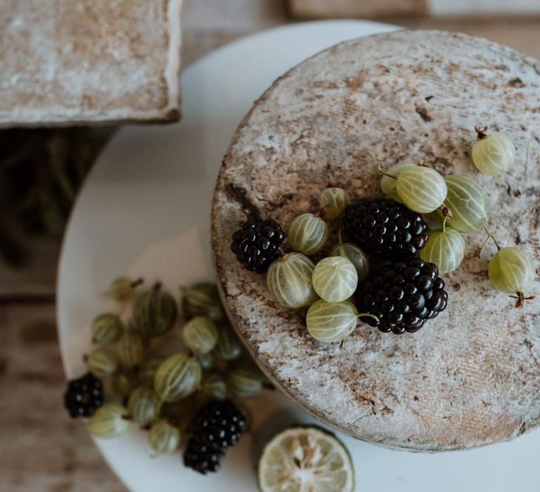 Top down shot of cheese wheel garnished with gooseberries and blackberries