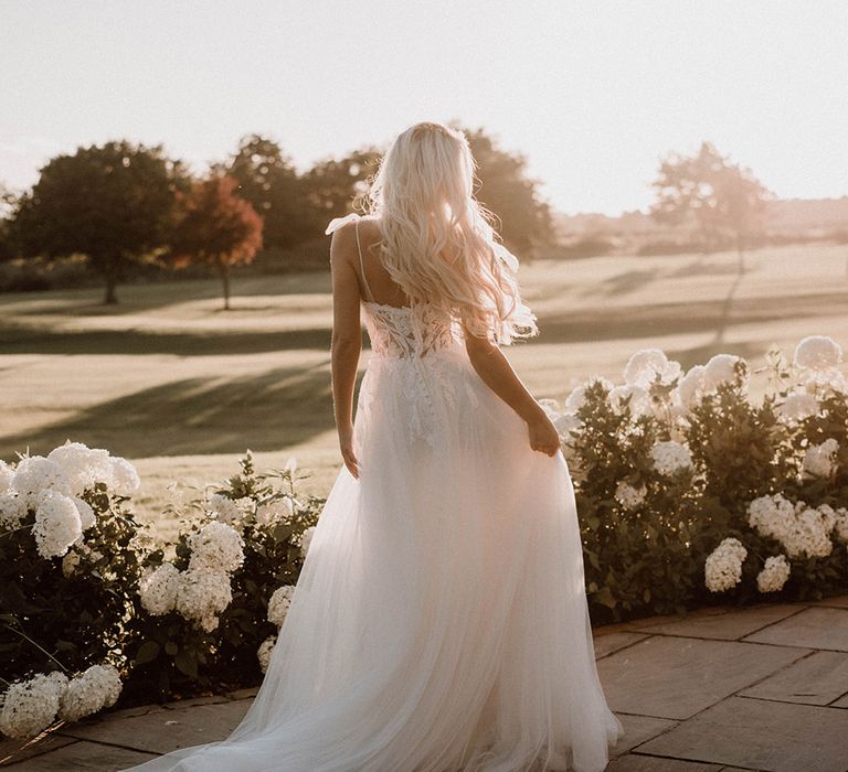 Bride in a tulle wedding dress standing outside Pryors Hayes wedding venue amongst the white hydrangeas