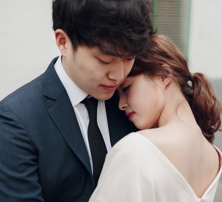 Close up of couple embracing, woman in cream dress, man in suit with black tie