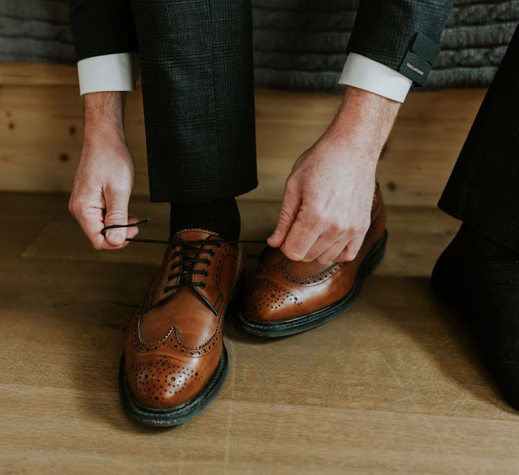 Groom on the wedding morning putting on his tan brogues 