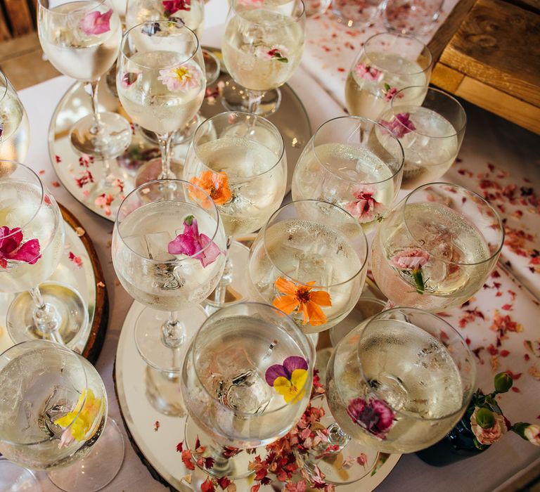 Wine glasses filled with water and edible colourful flowers