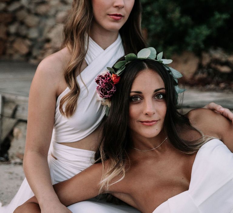 Two brides with eucalyptus head bands, wearing a strapless Jarlo London gown and an adjustable Kate's Dresses gown