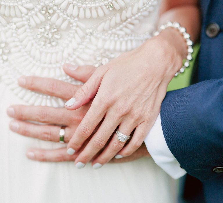 Bride places hand over grooms to show wedding rings