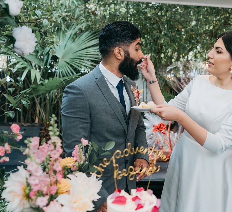 Bride feeds wedding cake to groom on their wedding day at their reception venue The Phene with botanical vibe