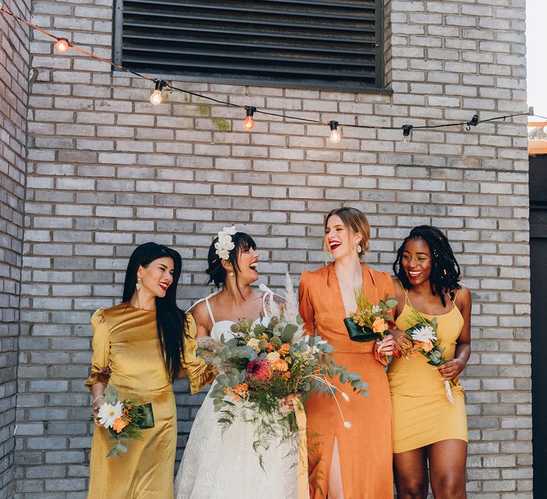 Bridesmaids in different coloured yellow and orange satin bridesmaid dresses in short, midi and full length designs 