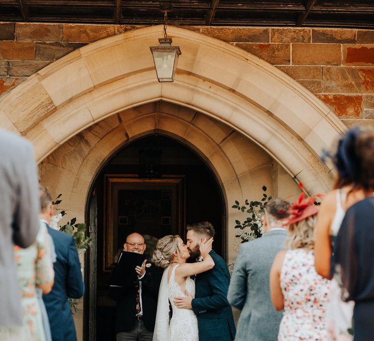 Bride and groom kiss at outdoor wedding ceremony at Plas Dinam country house venue in Wales